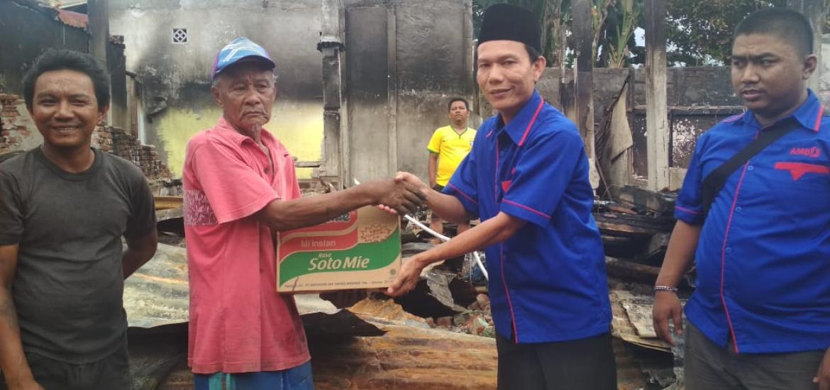 Ketua AMBO menyerahkan bantuan sembako kepada keluarga korban kebakaran